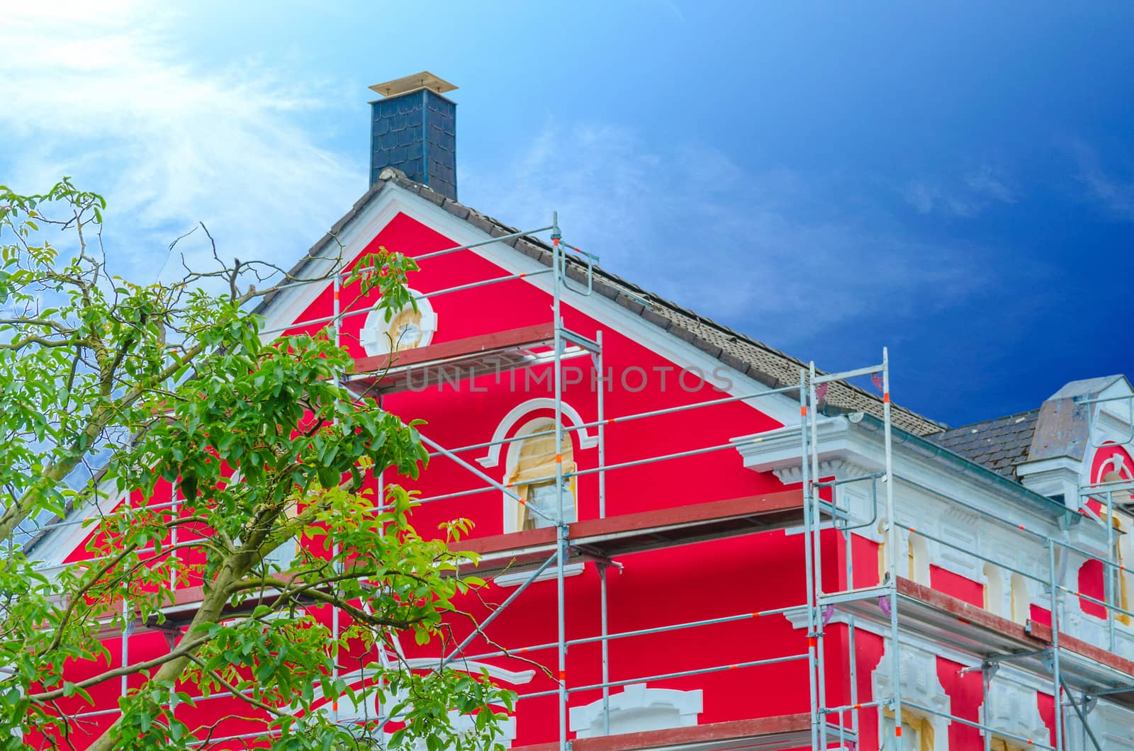 Detail red painted house facade with scaffolding in the background a dark blue sky.
