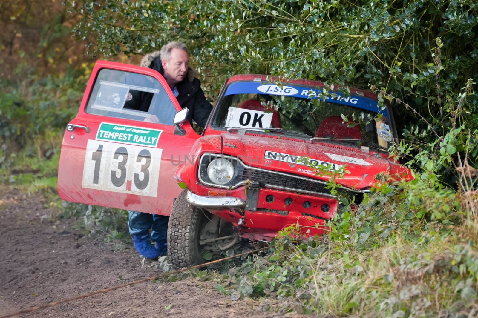Aldershot, UK - November 3, 2012: Safety crew helping to tow a wrecked Ford Escort out of the undergrow on the Pavillion stage of the MSA Tempest Rally near Aldershot, UK