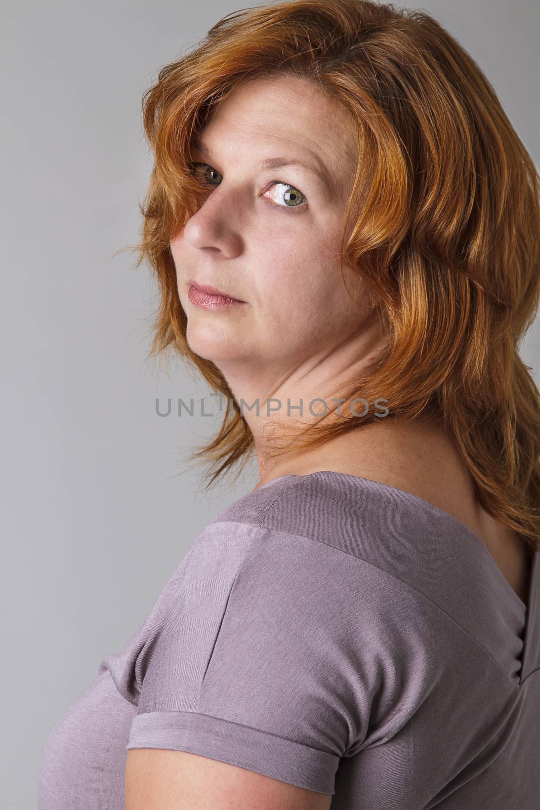 adult woman with red hair looking over her shoulder