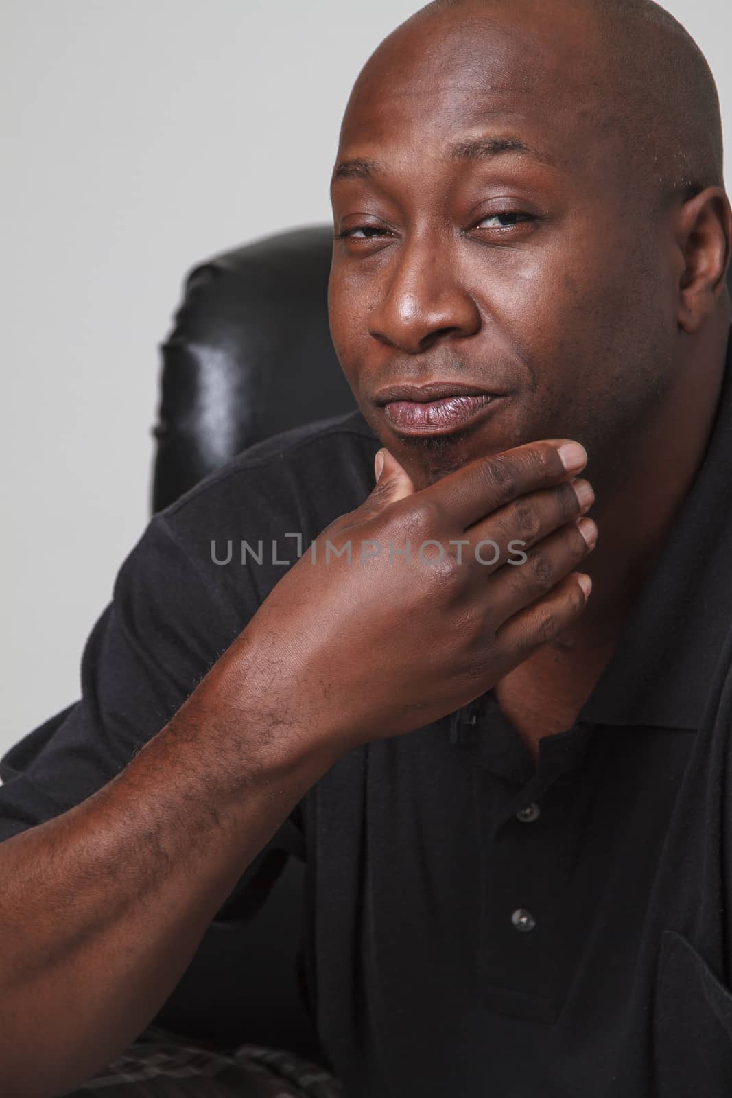 bald black man holding his chin and looking cool