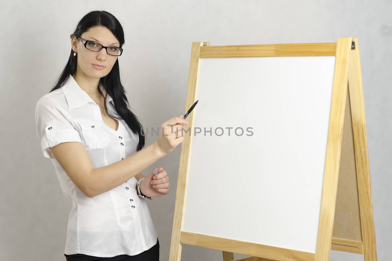 Business girl with glasses shows a marker on a white board