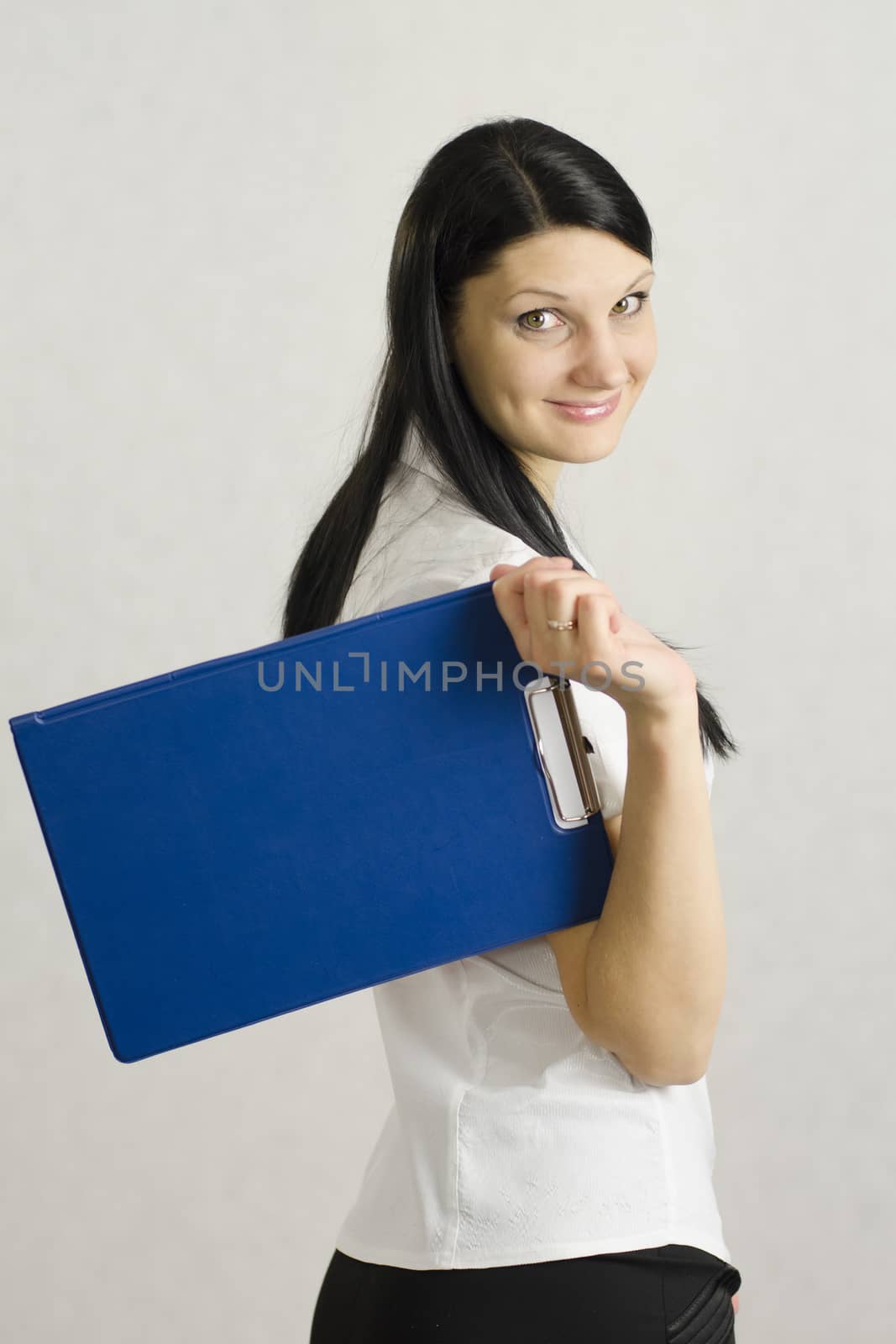 Business girl happily keeps the folder with the documents. The contents of the folder she pleased the client and the girl is very happy and cheerful. Studio, white background