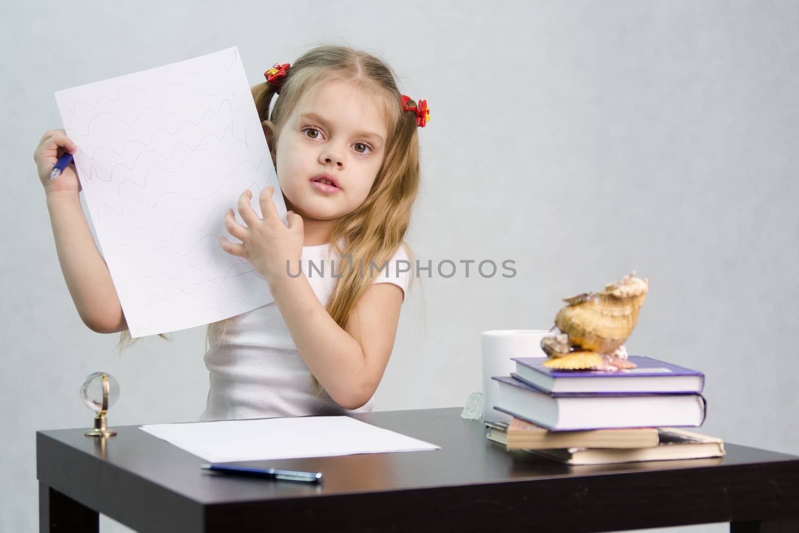girl sits at the table and shows written on a sheet of paper (Doodle). There are tombs of books, sheets of paper, a pen, glass globe, with a glass of tea, sea shell. The image of the writer.