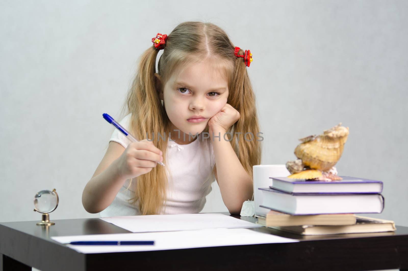 girl sits at a table and wrote on a sheet of paper. There are tombs of books, sheets of paper, a pen, glass globe, with a glass of tea, sea shell. The image of the writer