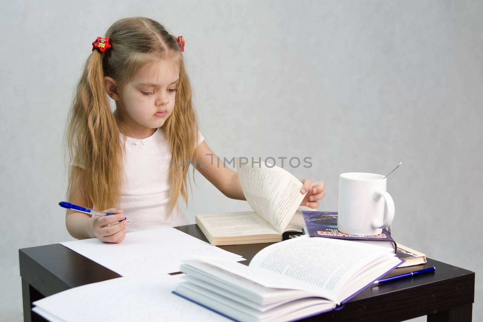 girl sits at a table and flips through the book and writes out the information you need. Next are still books, sheets of paper, a pen, a glass of tea. The image of a student, a pupil, a teacher and literary critic
