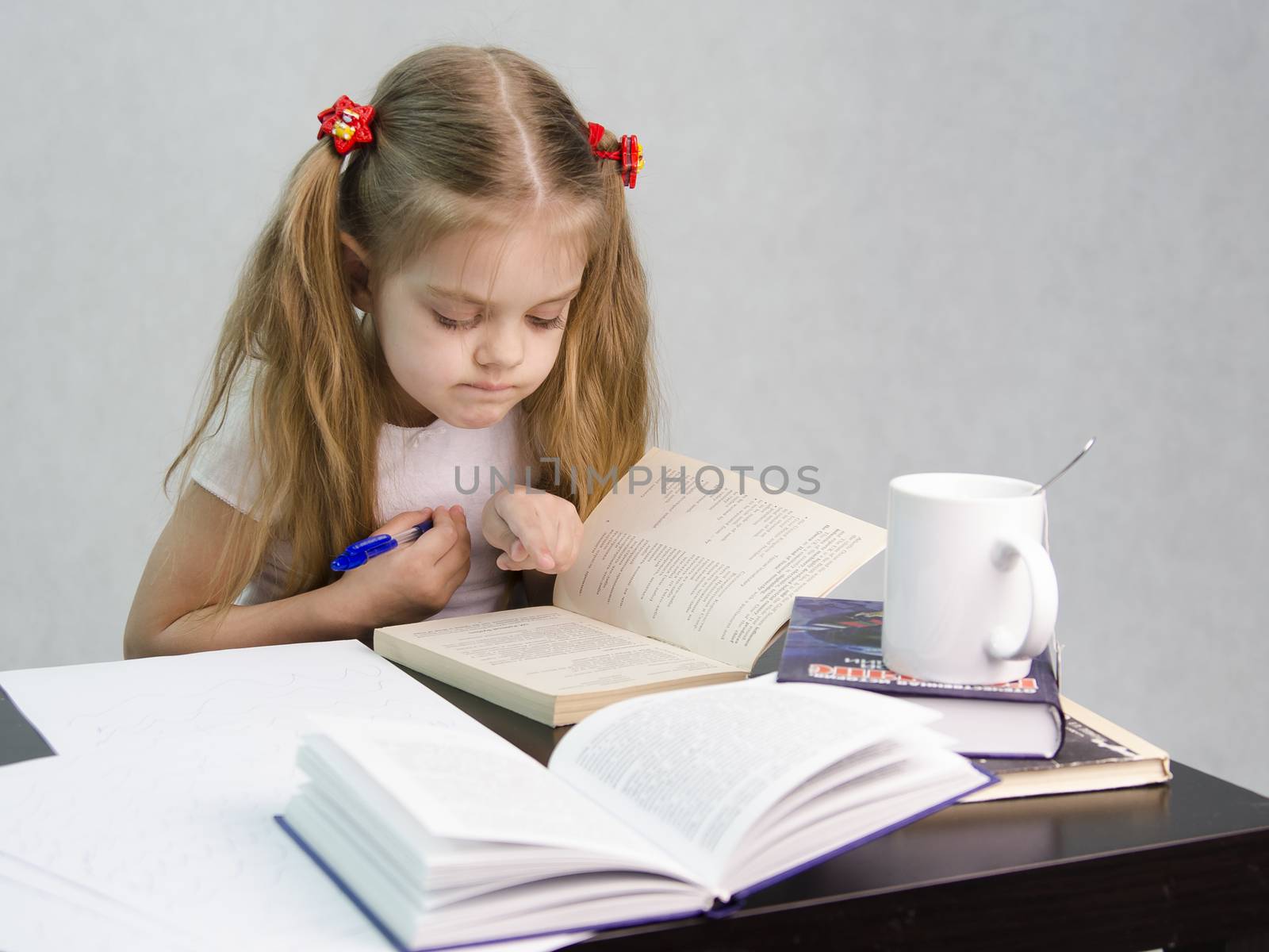 girl sits at a table and flips through the book and writes out the information you need. Next are still books, sheets of paper, a pen, a glass of tea. The image of a student, a pupil, a teacher and literary critic
