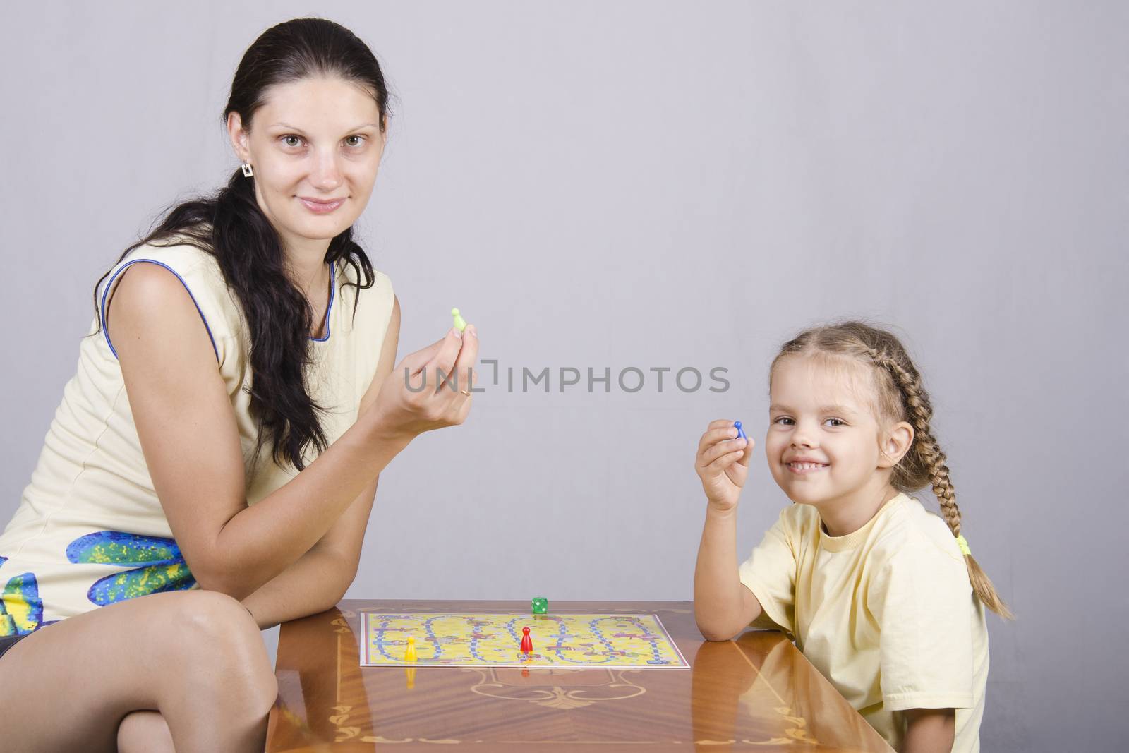 Mother and daughter sitting at a table and play a Board game