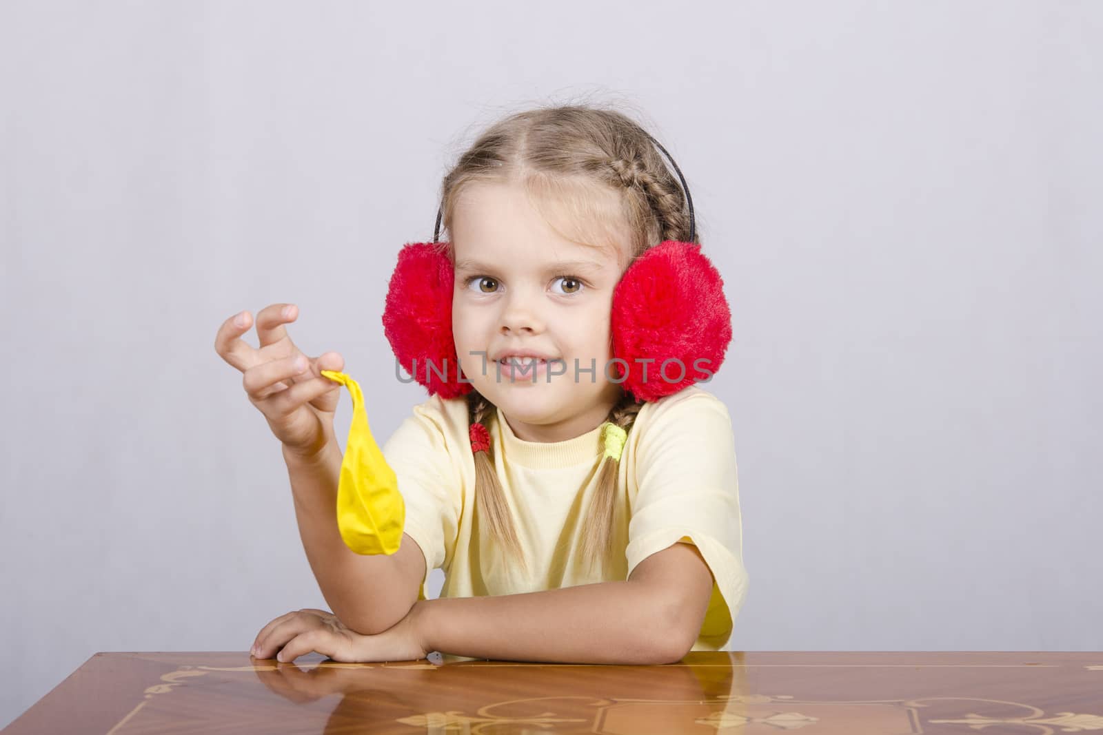 A child of four years in the headphones and with ������������ yellow ball is sitting at the table