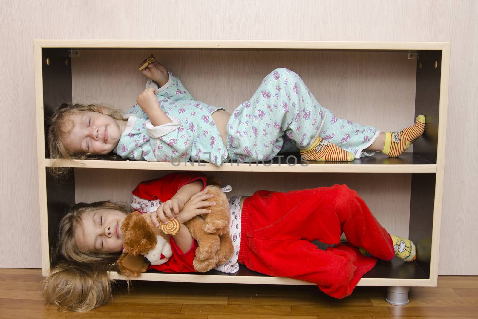 Two children lay on the shelf stands, with closed eyes. Much like a car with reserved seats
