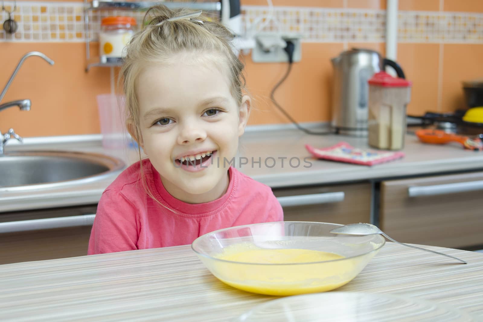 Girl five years eats porridge, sitting at the kitchen table.