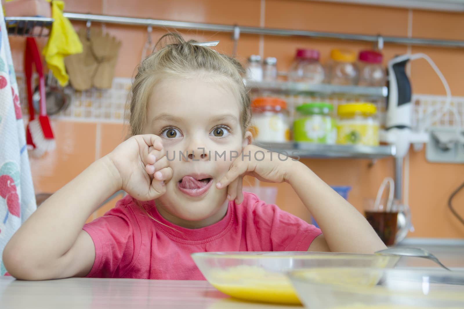 Girl five years eats porridge, sitting at the kitchen table.