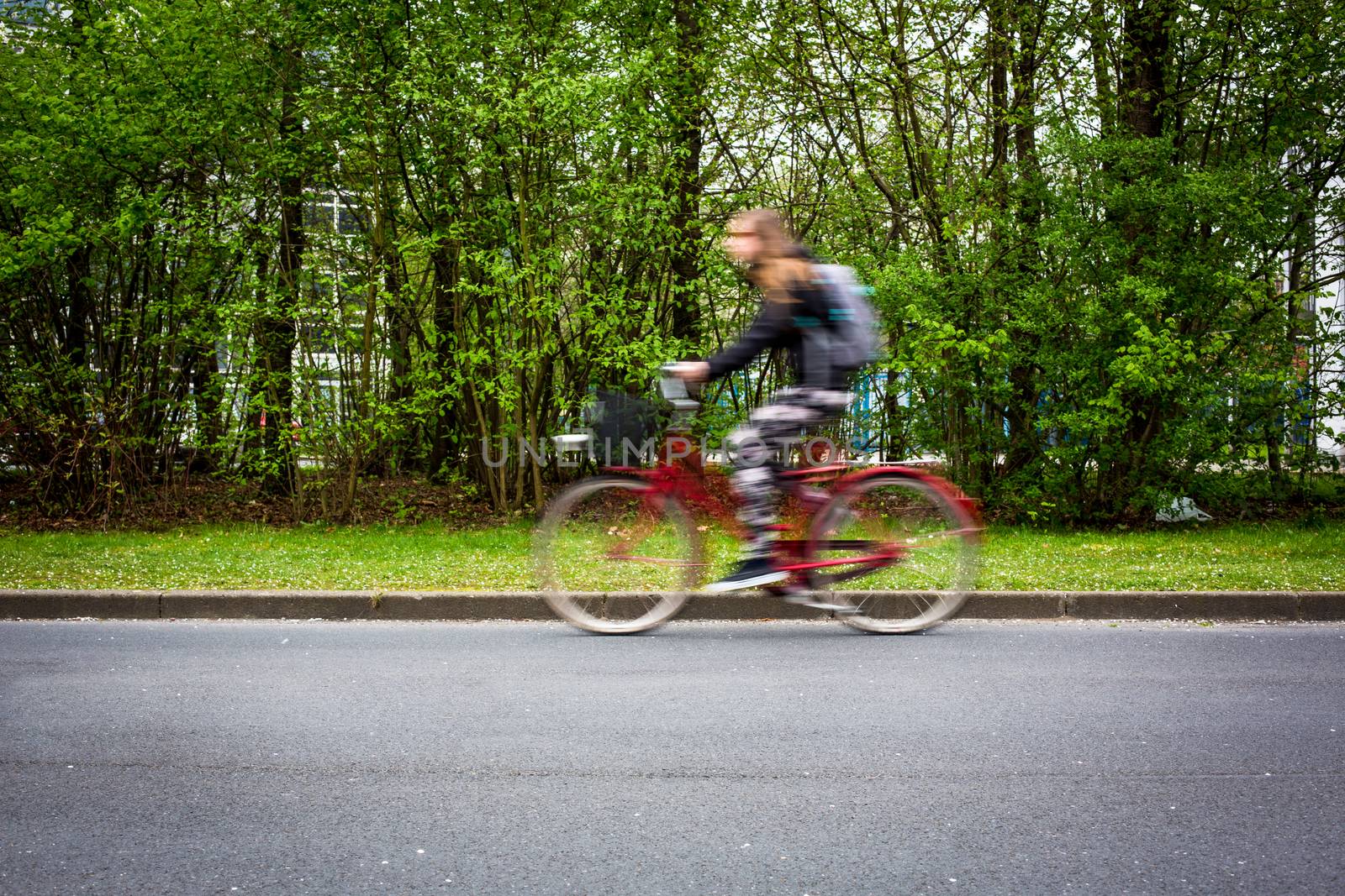Motion blurred female biker on a city street, going fast