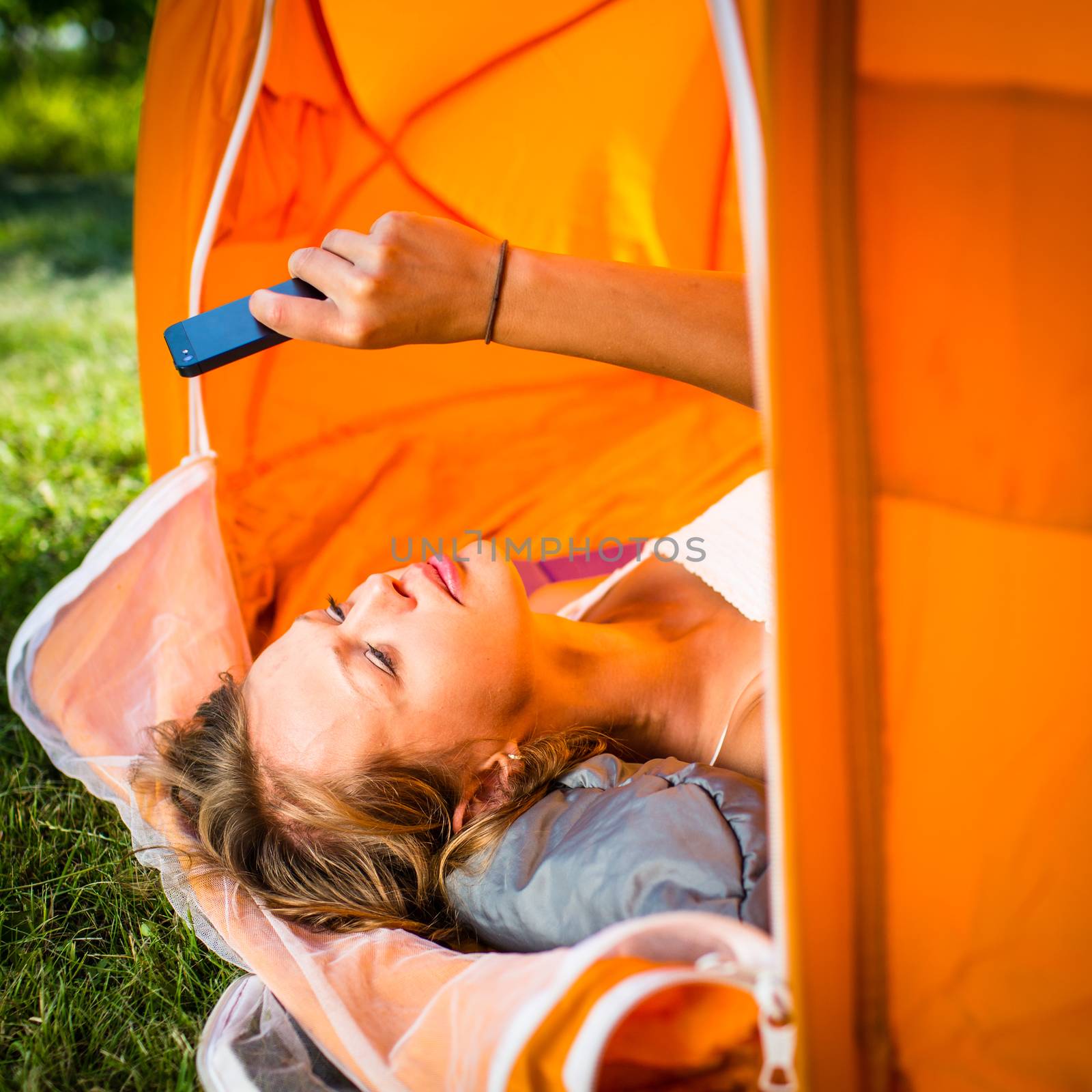 Pretty, young woman camping outdoors, lying in the tent by viktor_cap