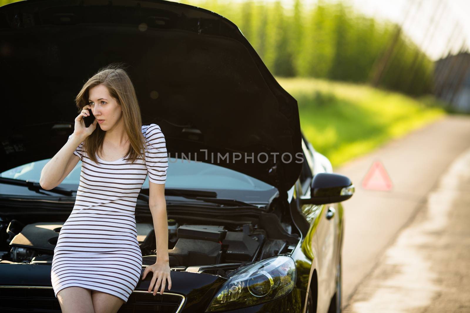 Pretty, young woman calling the roadside service/assistance after her car has broken down