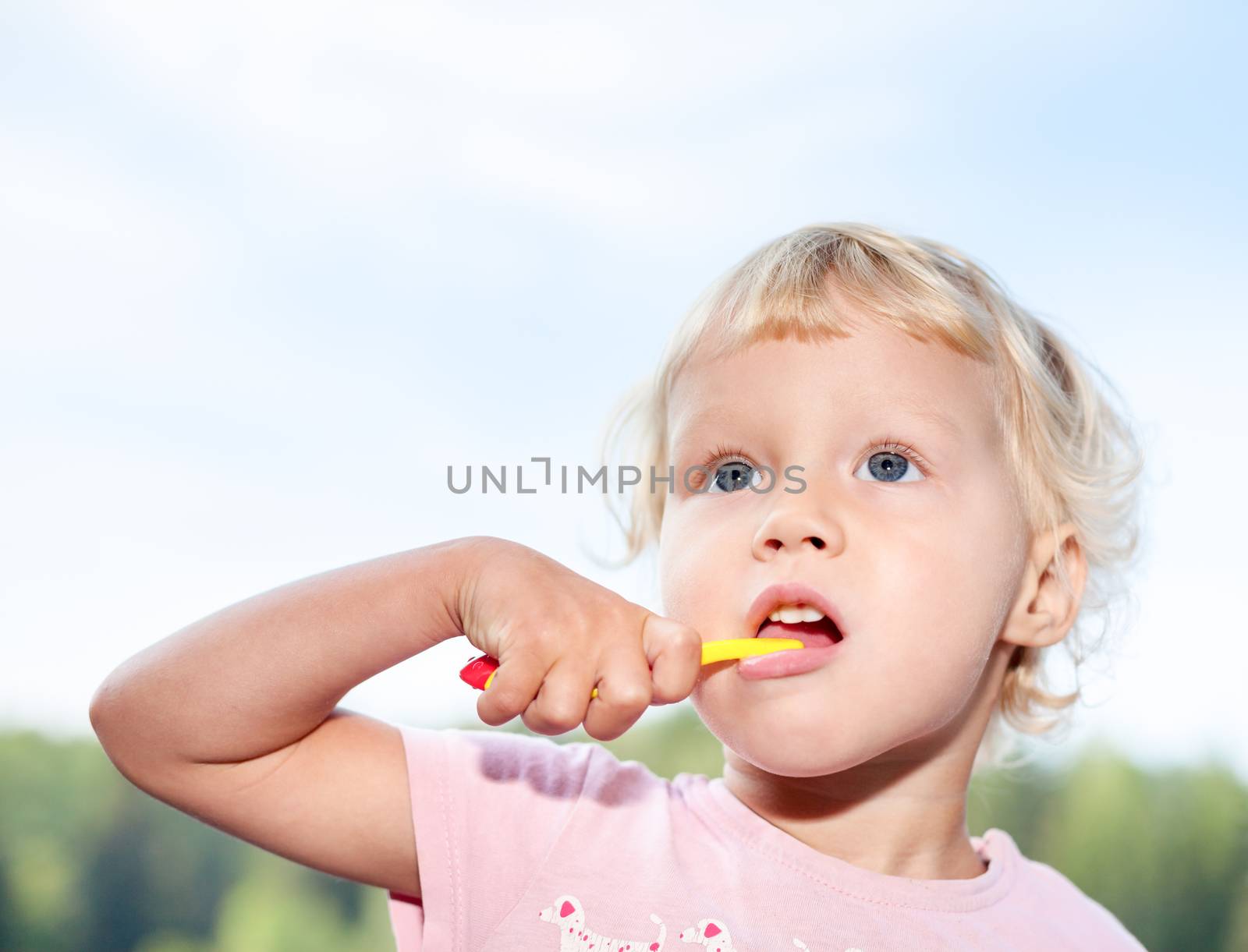Portrait of cute little girl brushing teeth outdoor