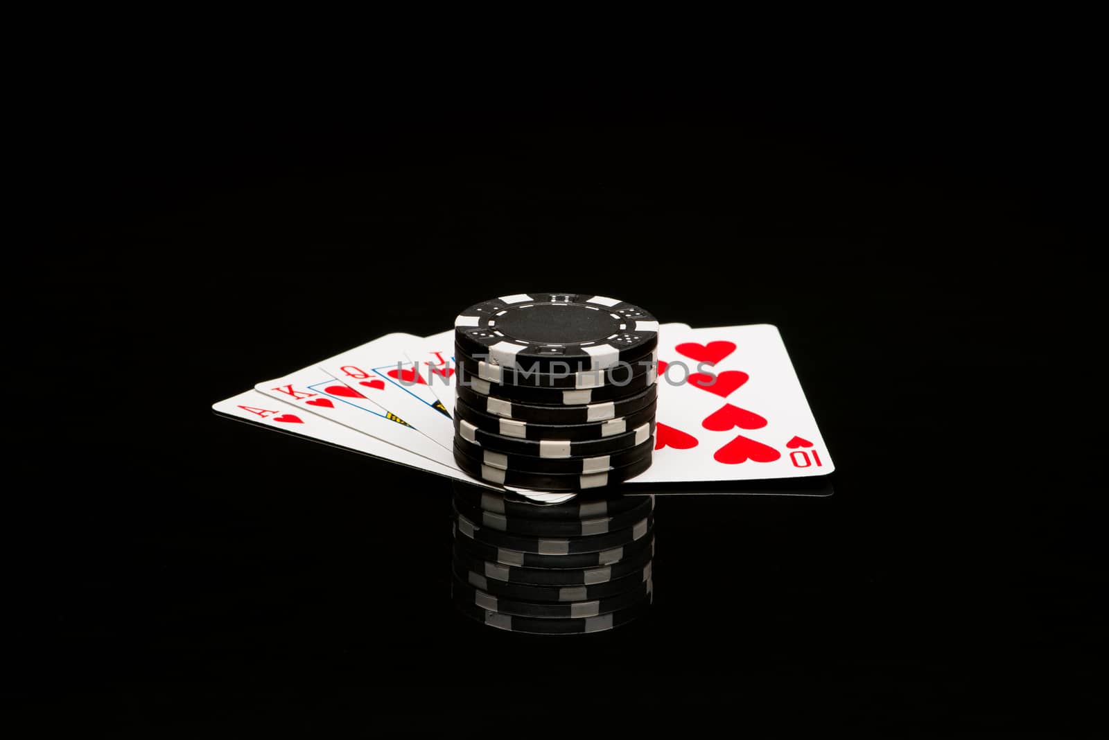 Poker cards and chips on black background with reflexion