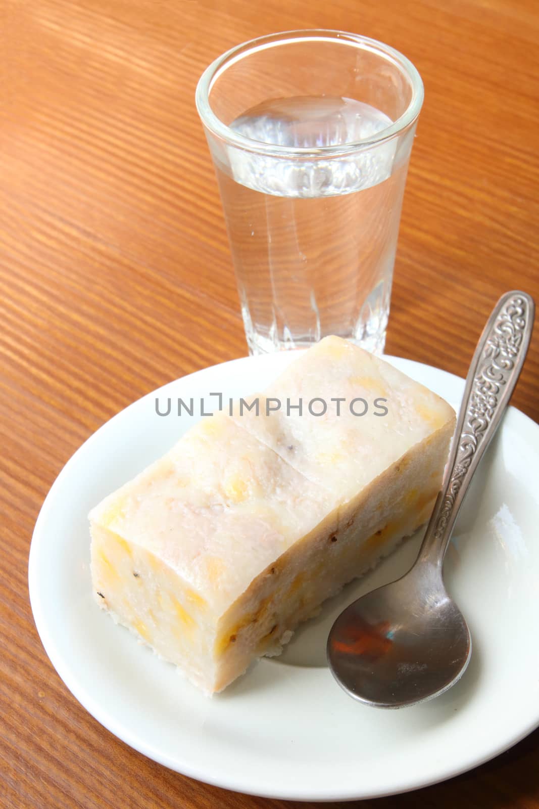 Thai dessert made from banana and coconut serve with a glass of water.