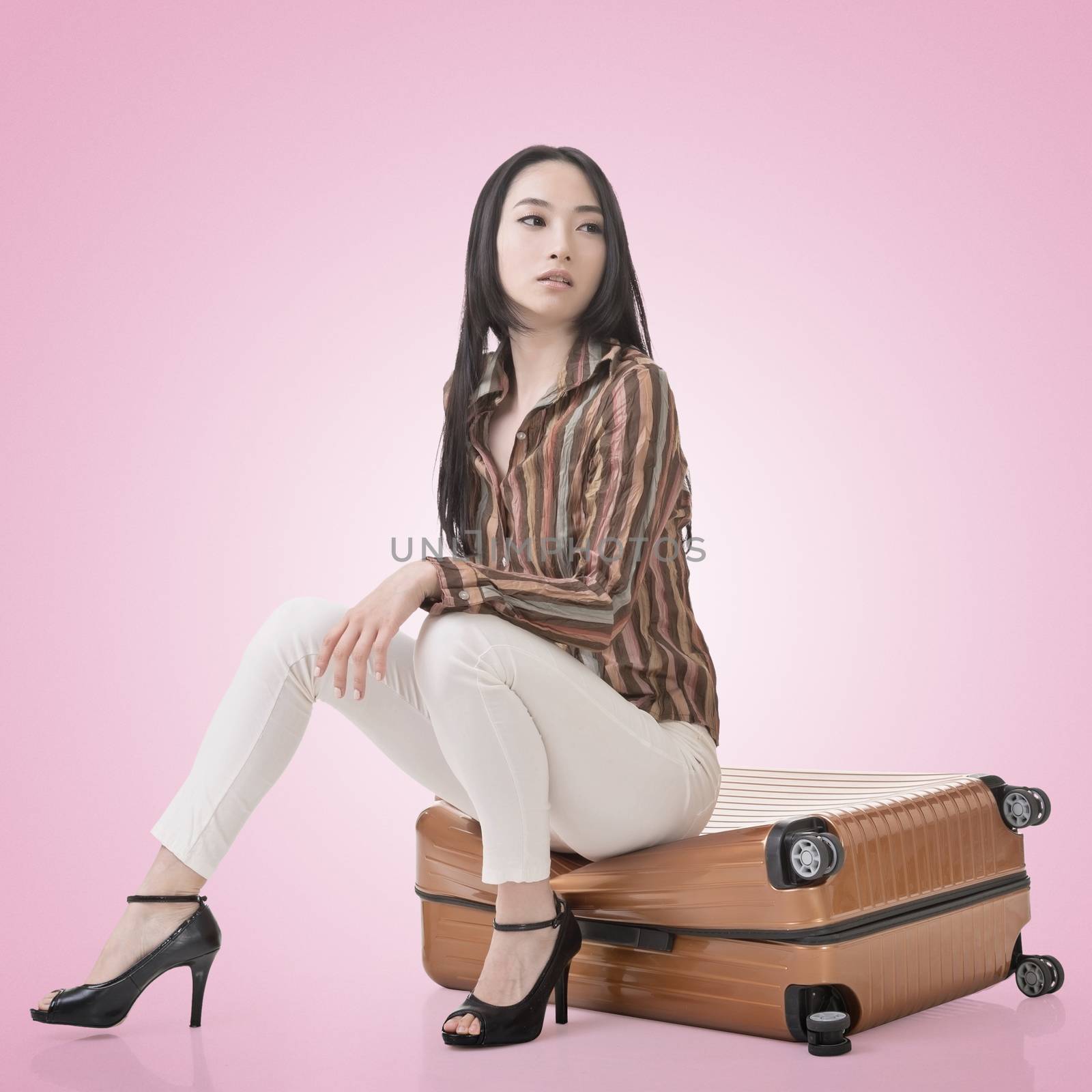 Asian woman thinking and sitting on a luggage.