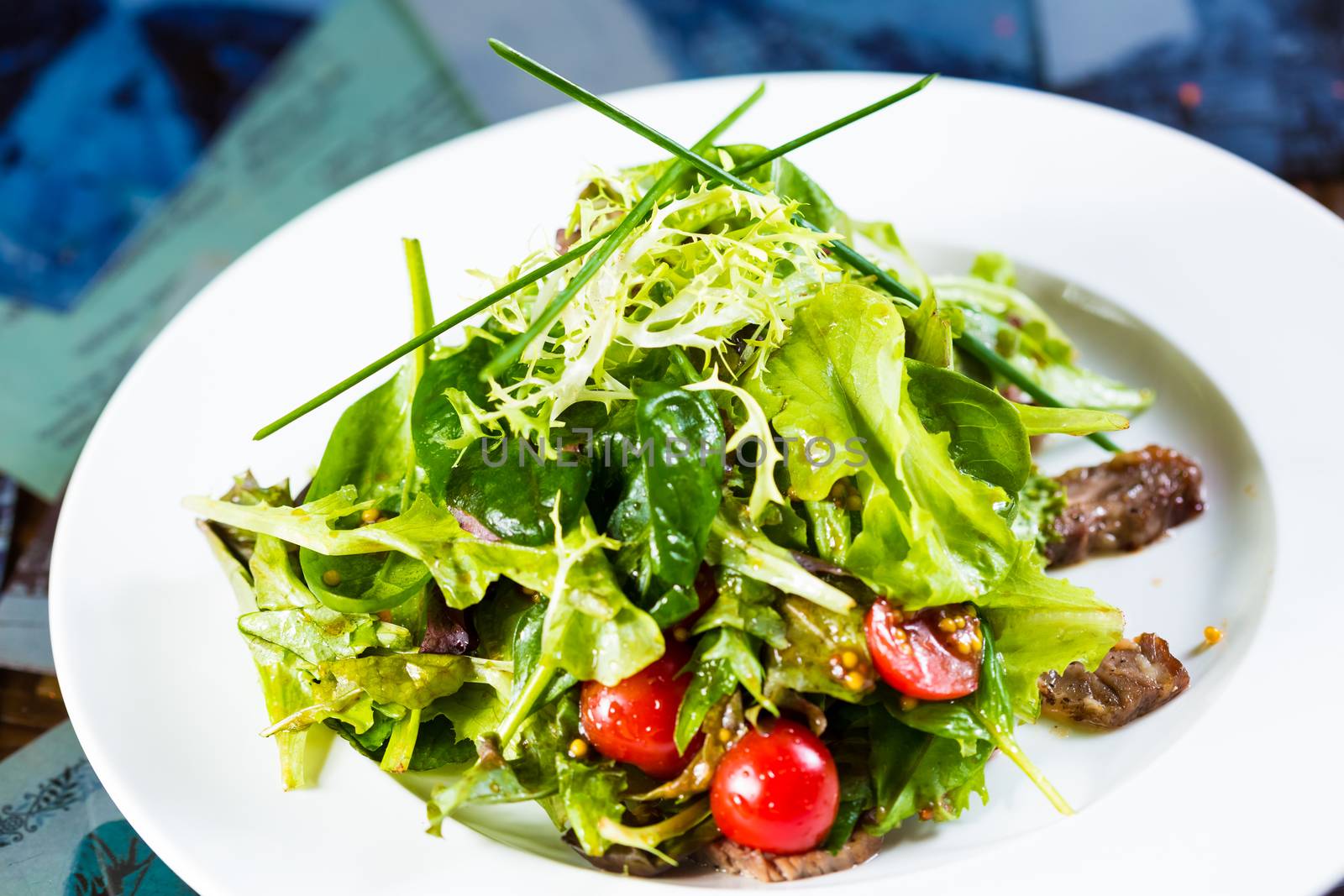 Fresh vegetable salad with meat and cherry tomatoes on white plate. by sarymsakov