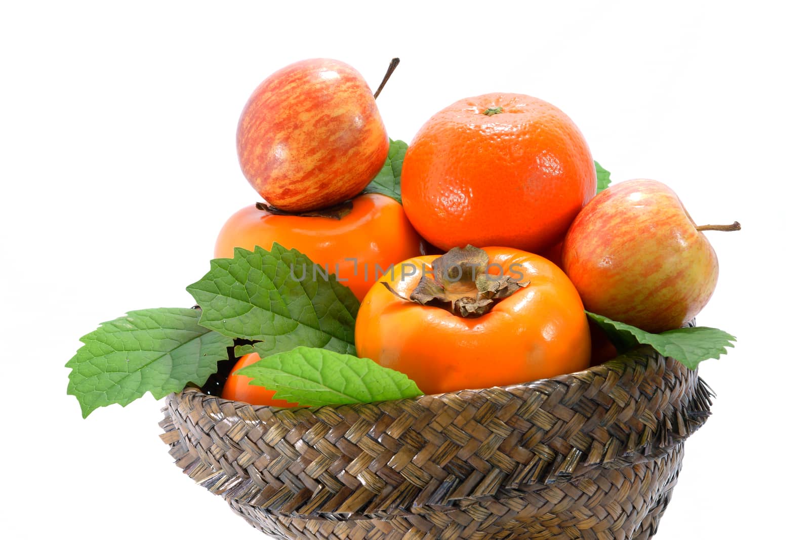 Orange, apple and persimmon in the basket of papyrus.