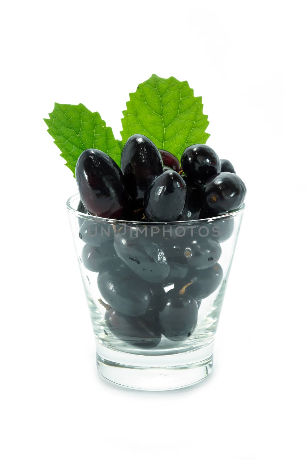 Black grapes in a glass isolated on a white background.