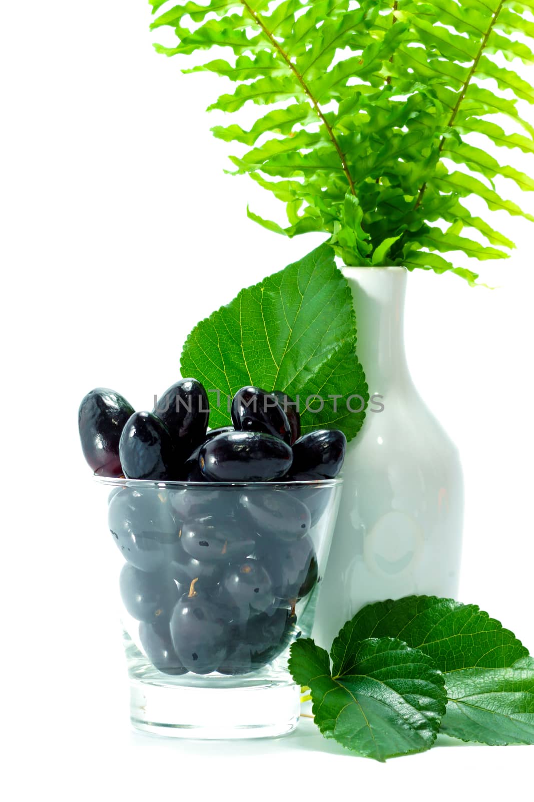Black grapes in a glass isolated on a white background.