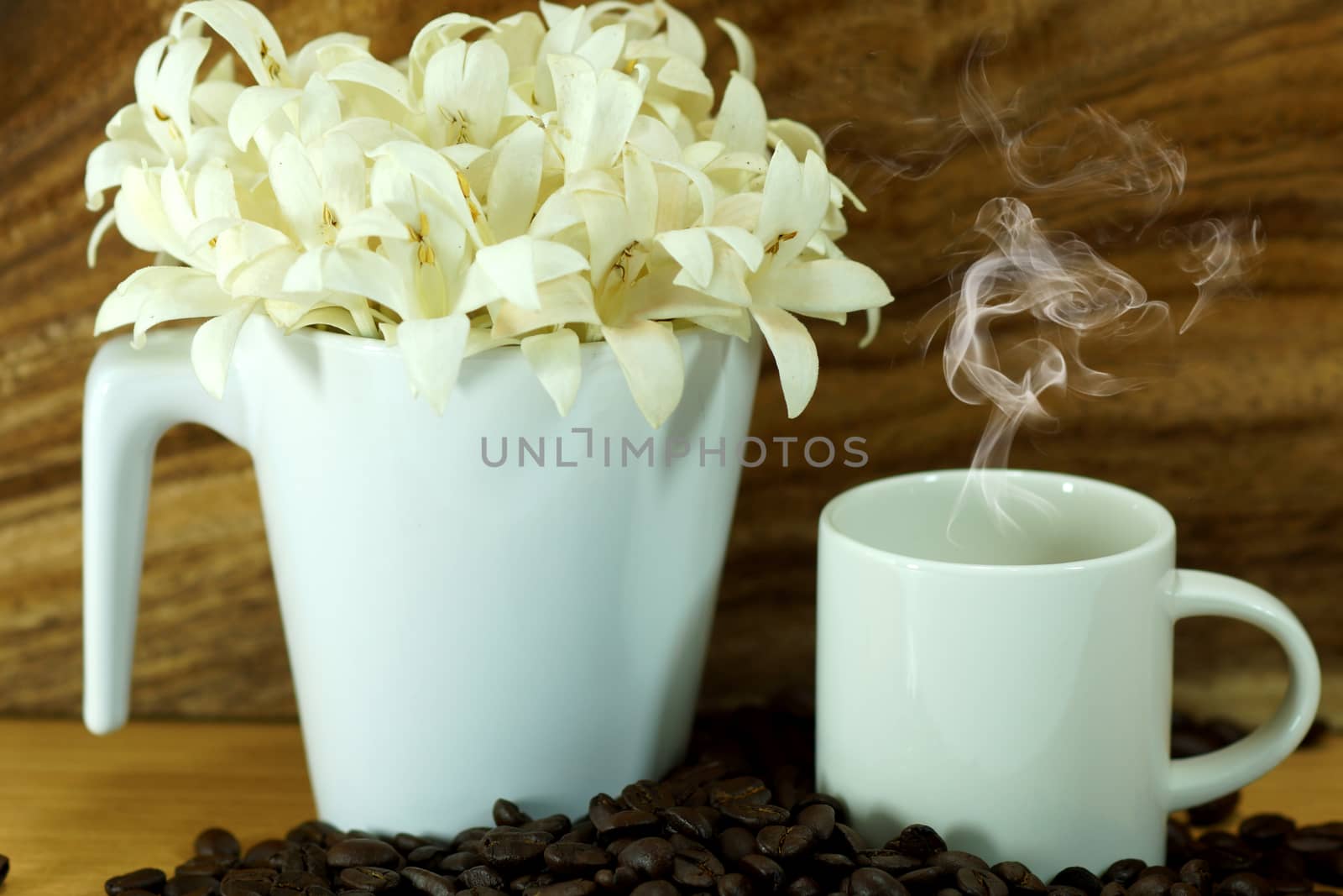 Fragrant white flowers in a glass on wooden background. by Noppharat_th