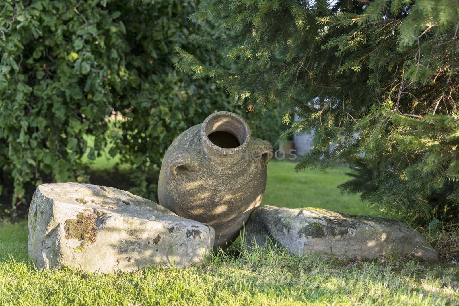 old concrete vase and rocks as garden decoaration