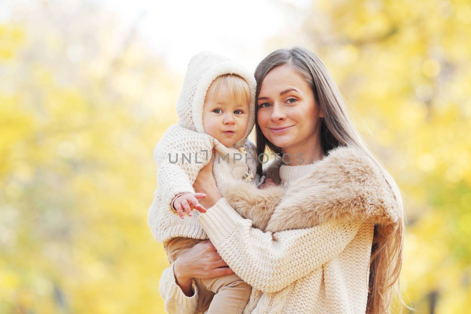 Beautiful young mother and her daughter in autumn park