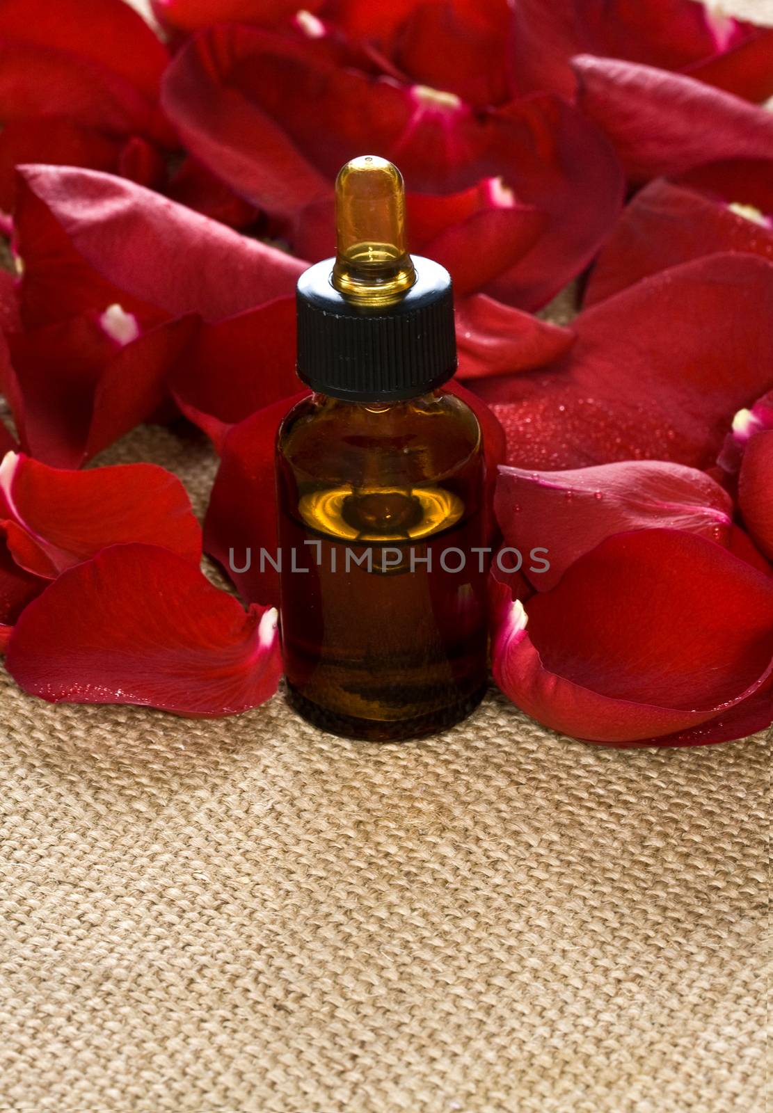 Red rose petals and massage oil on sackcloth