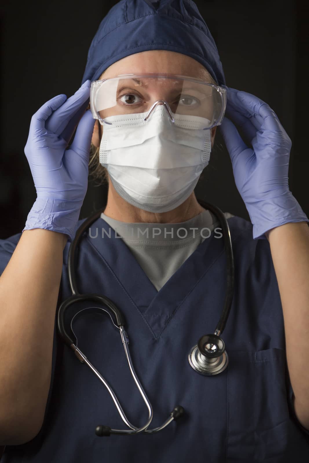 Female Doctor or Nurse Putting on Protective Facial Wear by Feverpitched