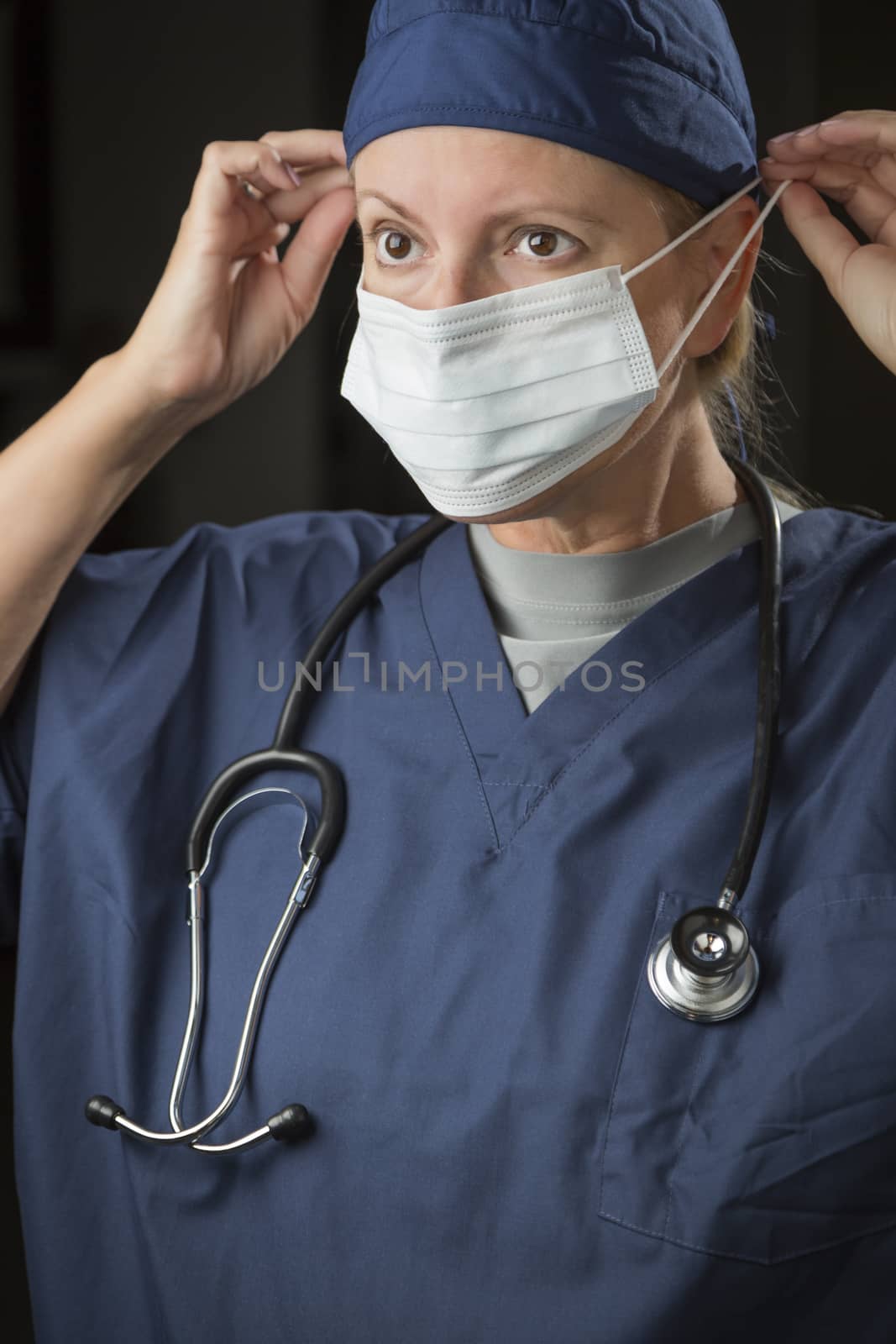 Female Doctor or Nurse Putting on Protective Face Mask by Feverpitched