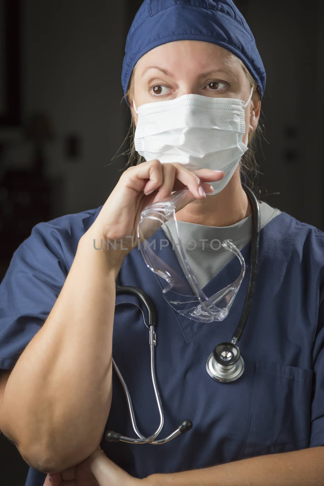 Concerned Female Doctor or Nurse Wearing Protective Face Mask and Holding Protective Eye Glasses.