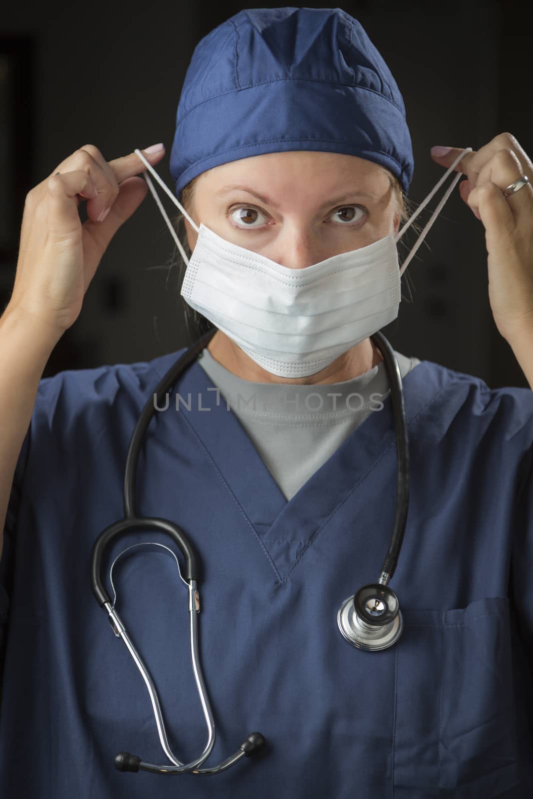 Female Doctor or Nurse Putting on Protective Face Mask by Feverpitched