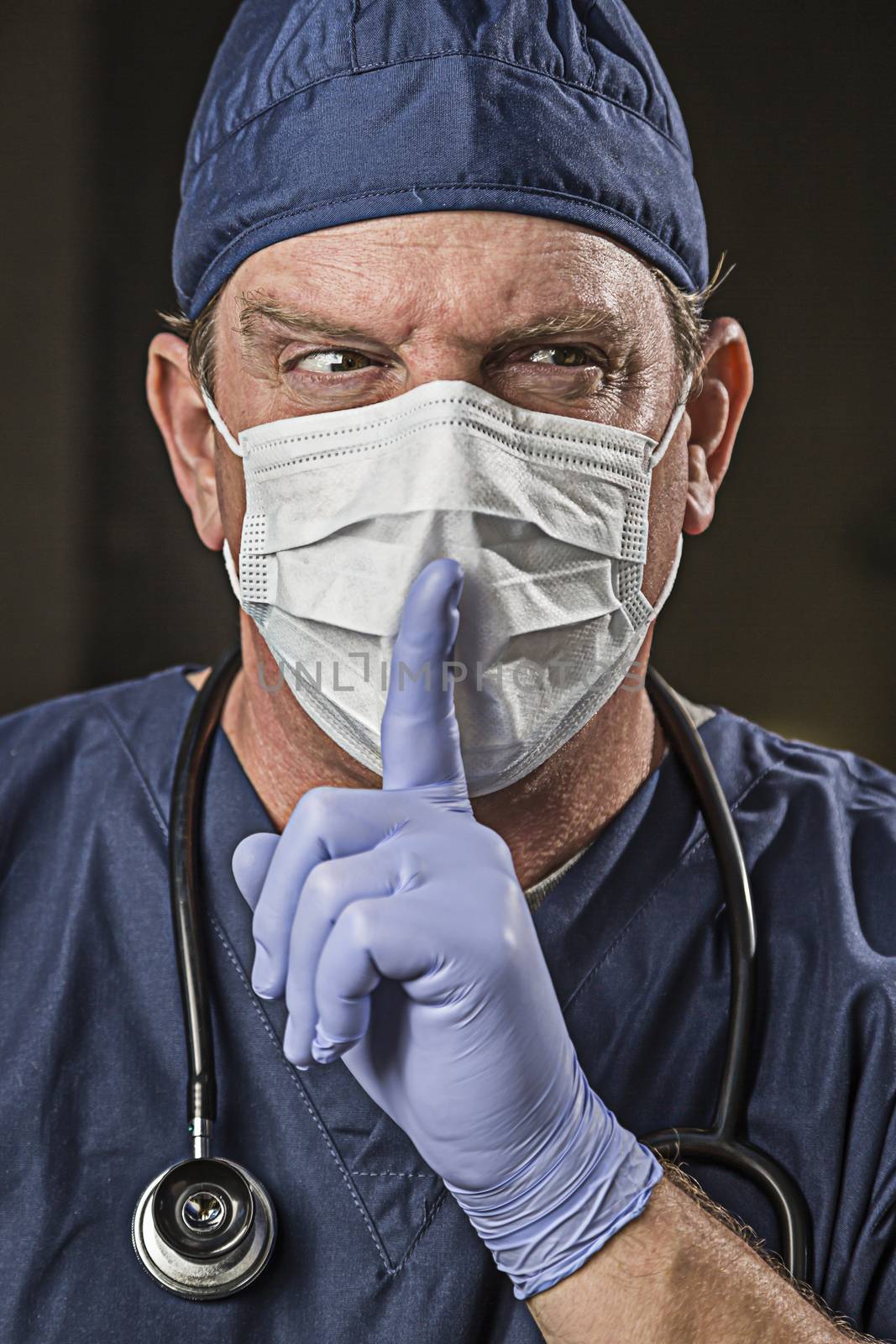 Secretive Doctor or Nurse With Finger in Front of Mouth wearing Protective Wear and Stethoscope.