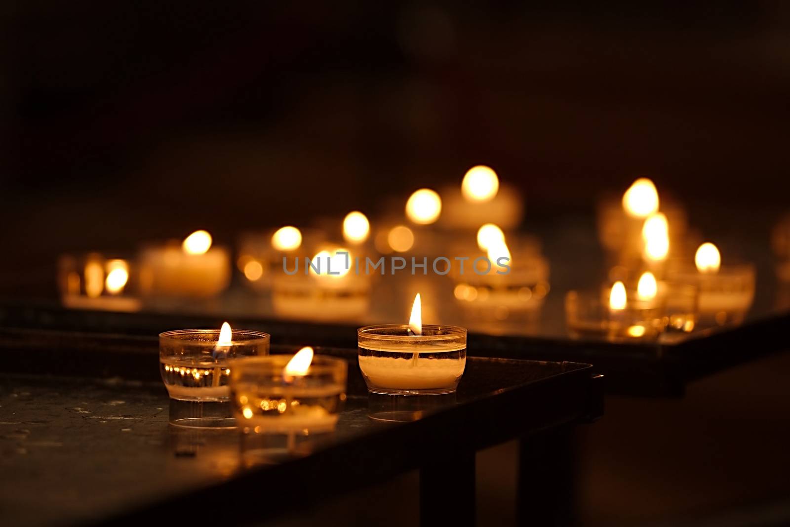 Rows of burning candles in a dim church