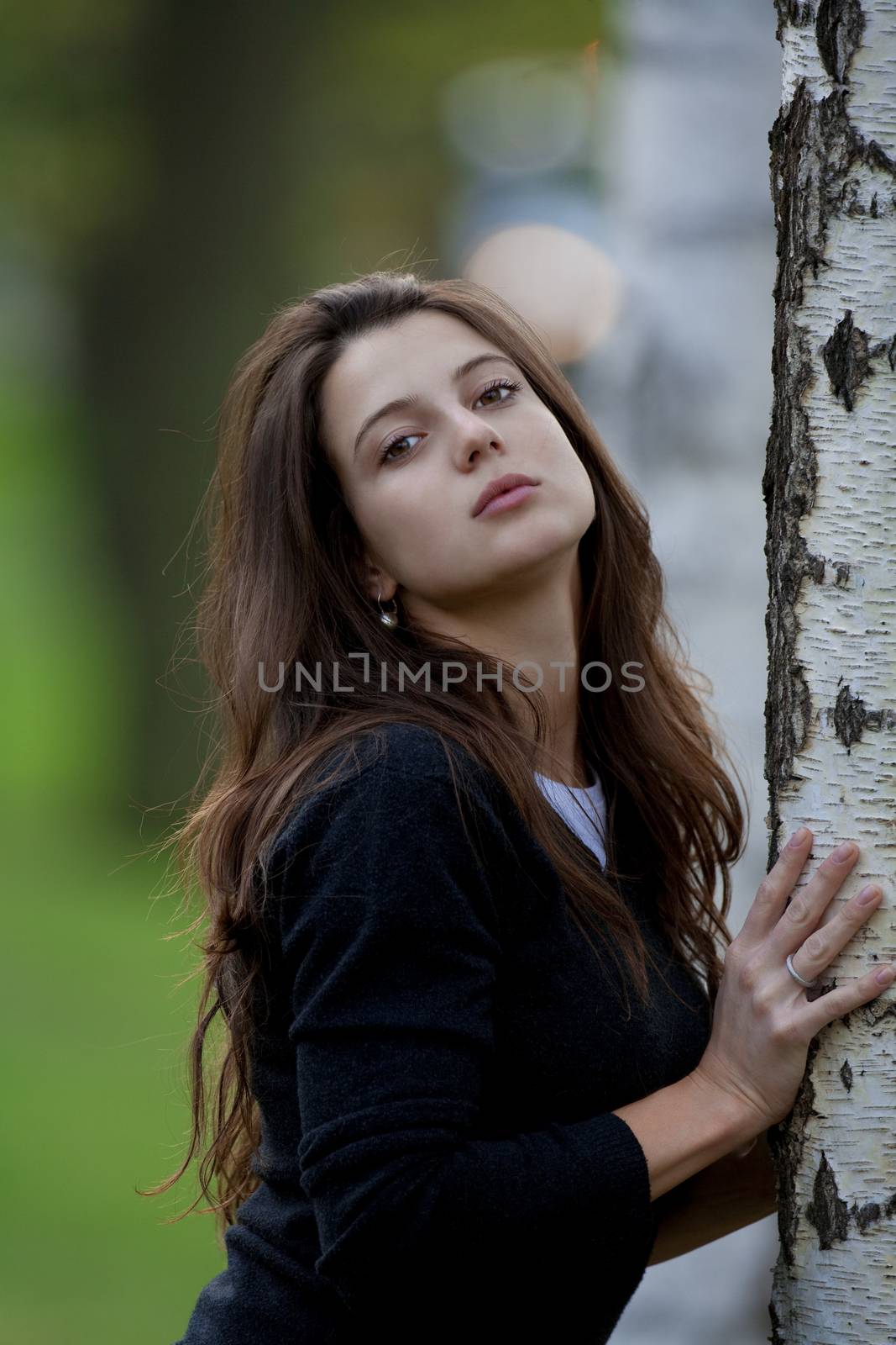 portrait of a beautiful brunette standing in birch forest