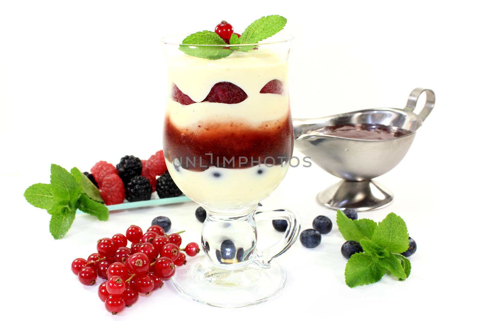 a dessert in a glass, layered with pudding, red stewed fruit and berries