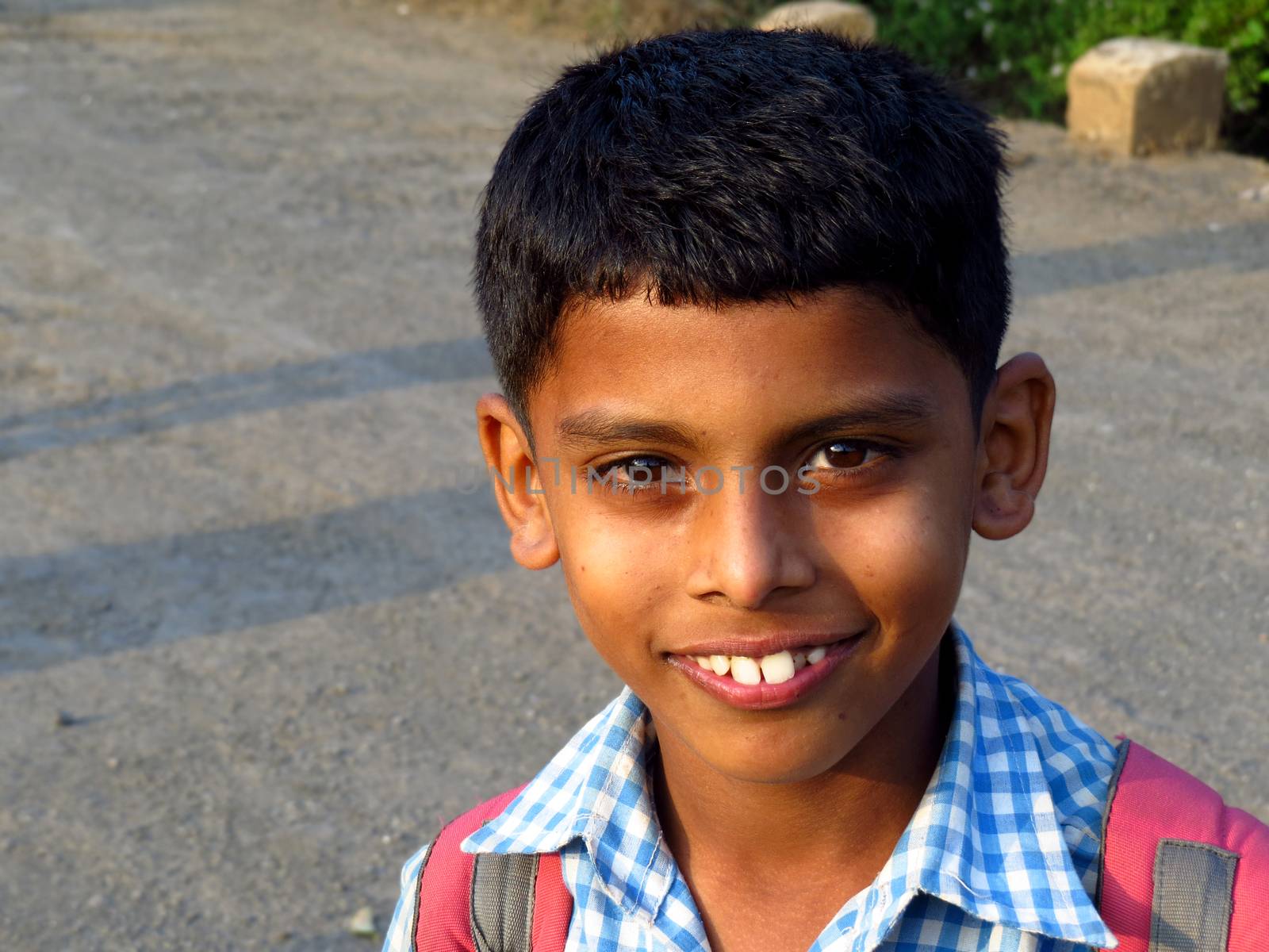A portrait of a cute Indian boy with his school bag.                               
