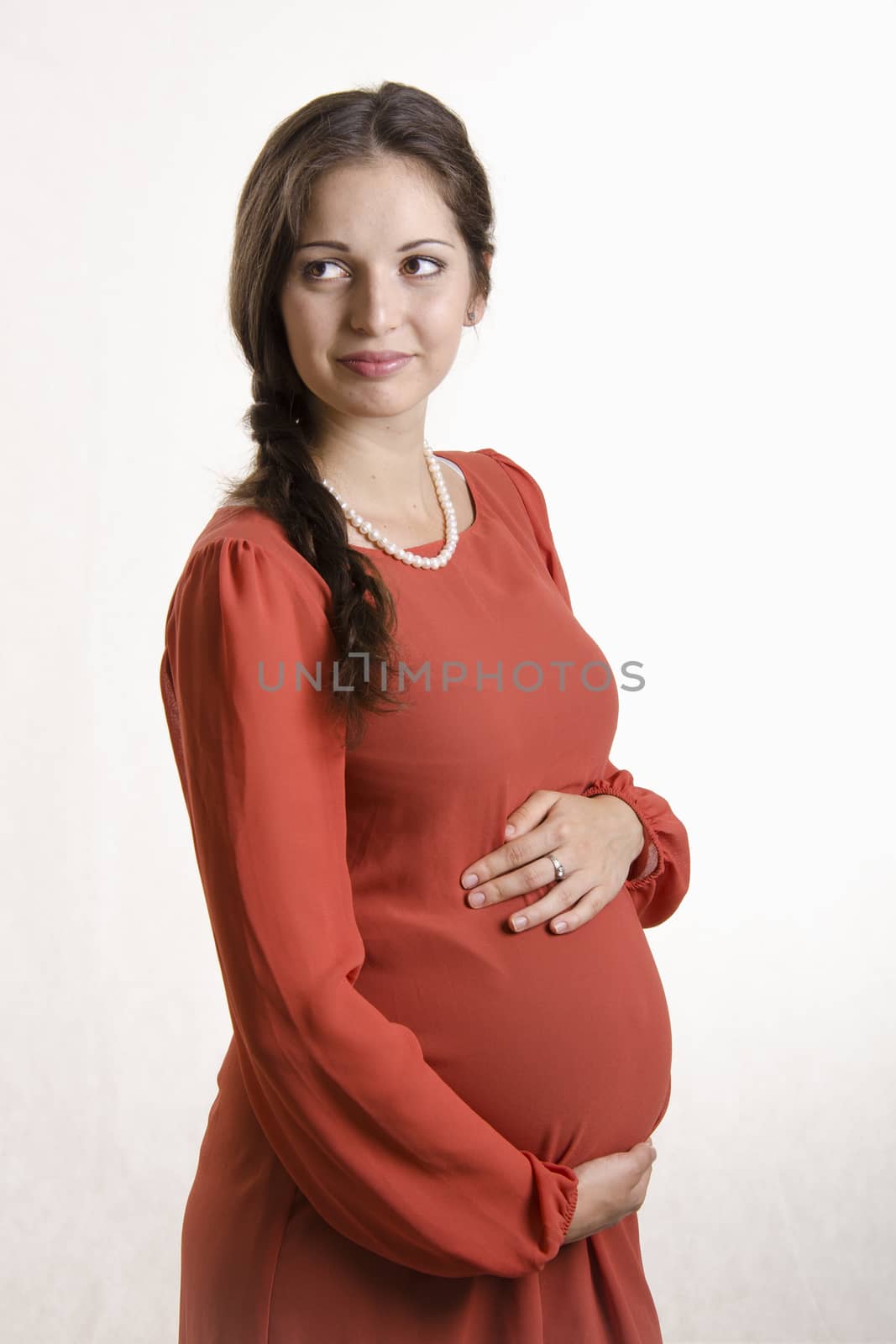 A half-length portrait of a pregnant girl in a beige tight dress