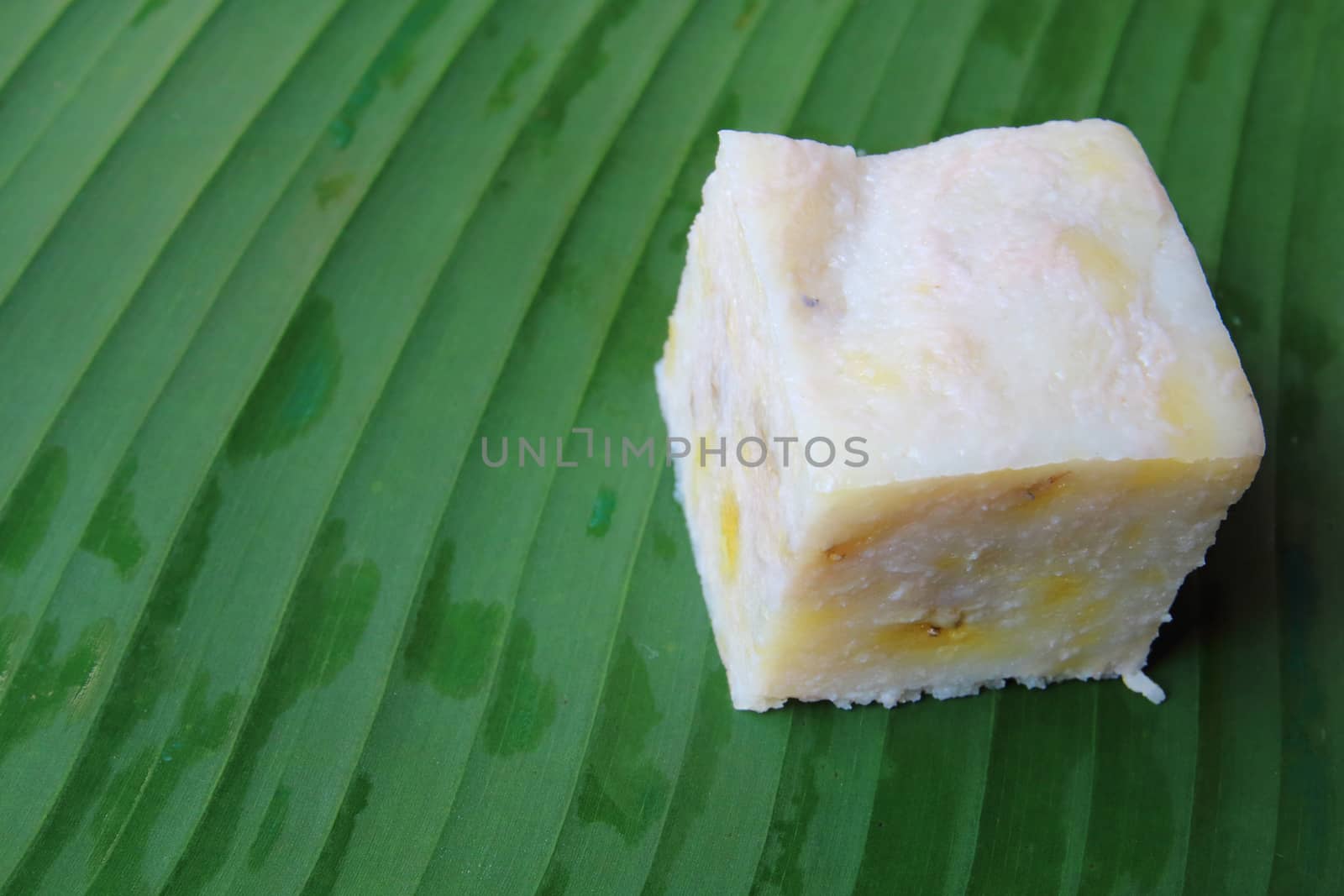 The cube of thai dessert made from banana put on banana leaf.