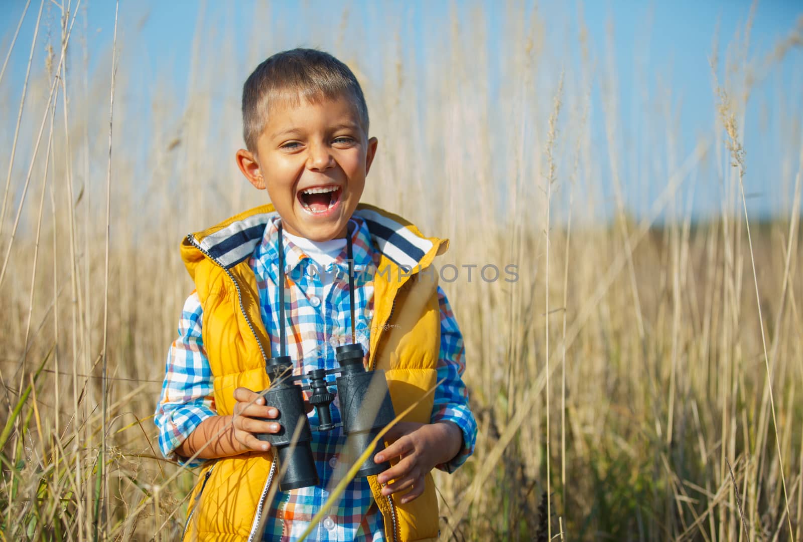 Young boy child playing pretend explorer adventure safari game outdoors with binoculars and bush hat