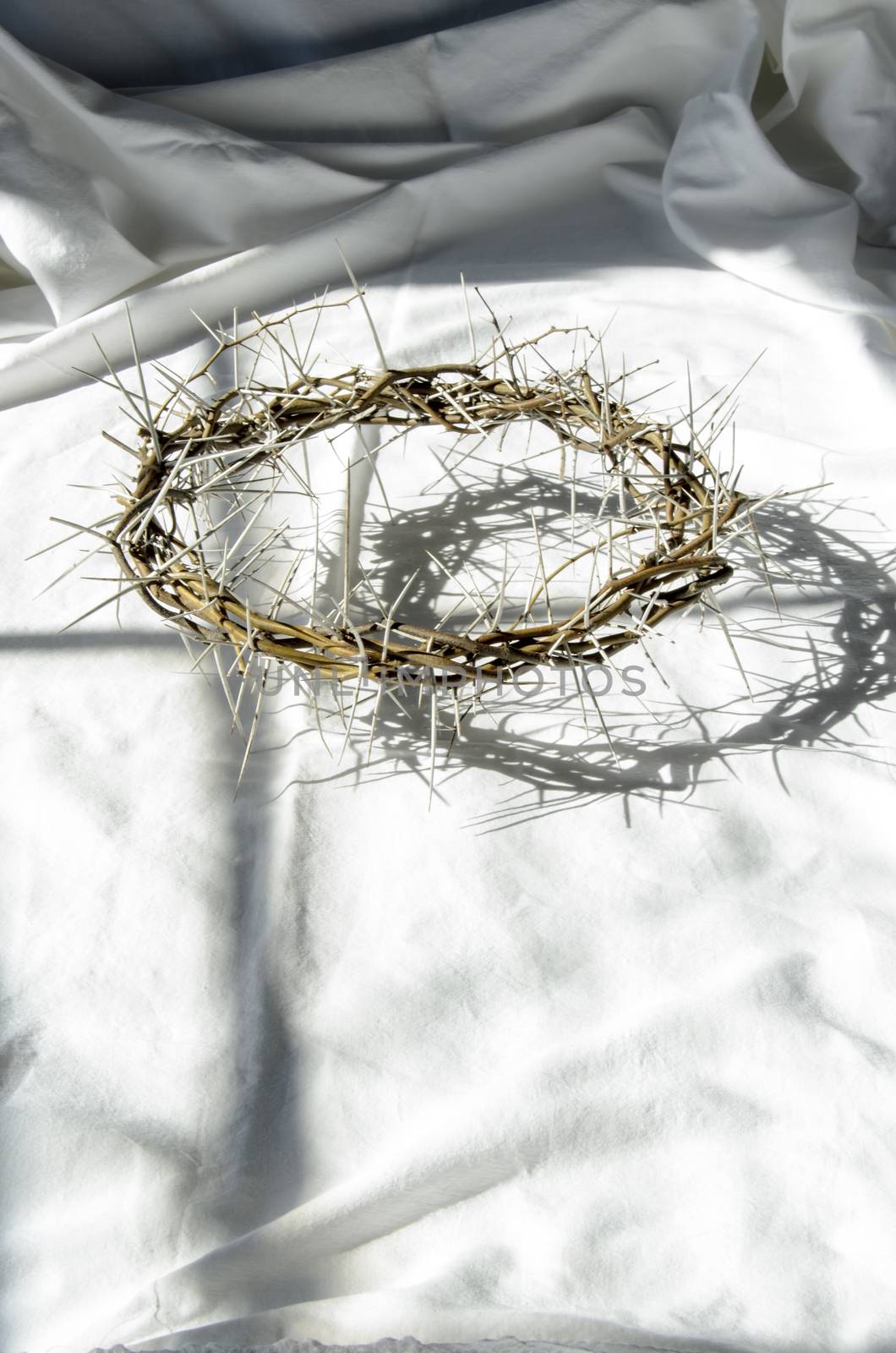 crown of thorns reminds the passion of the christ. resting on a white linen cloth with an olive branch