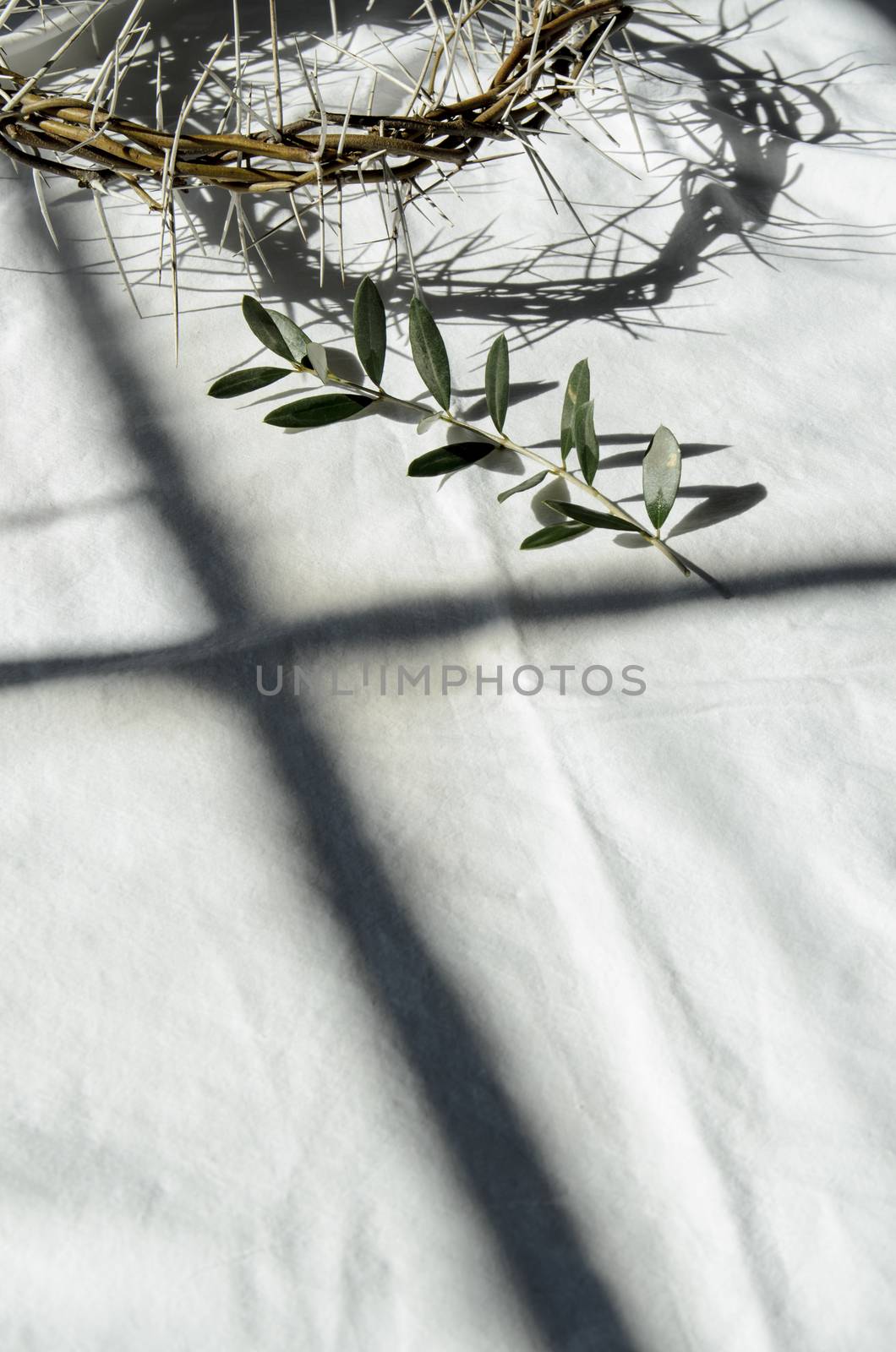 crown of thorns reminds the passion of the christ. resting on a white linen cloth with an olive branch