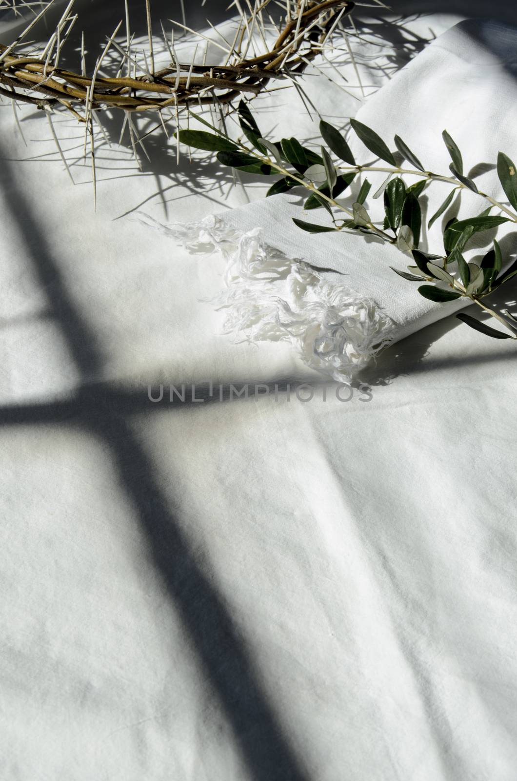 crown of thorns reminds the passion of the christ. resting on a white linen cloth with an olive branch