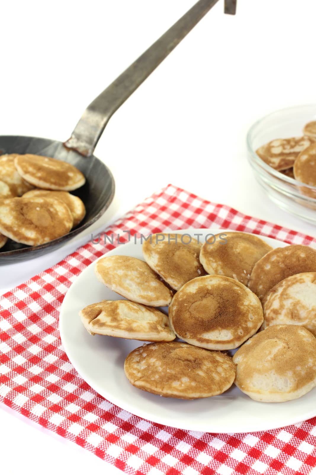 Dutch Poffertjes on a plate with pan before light background