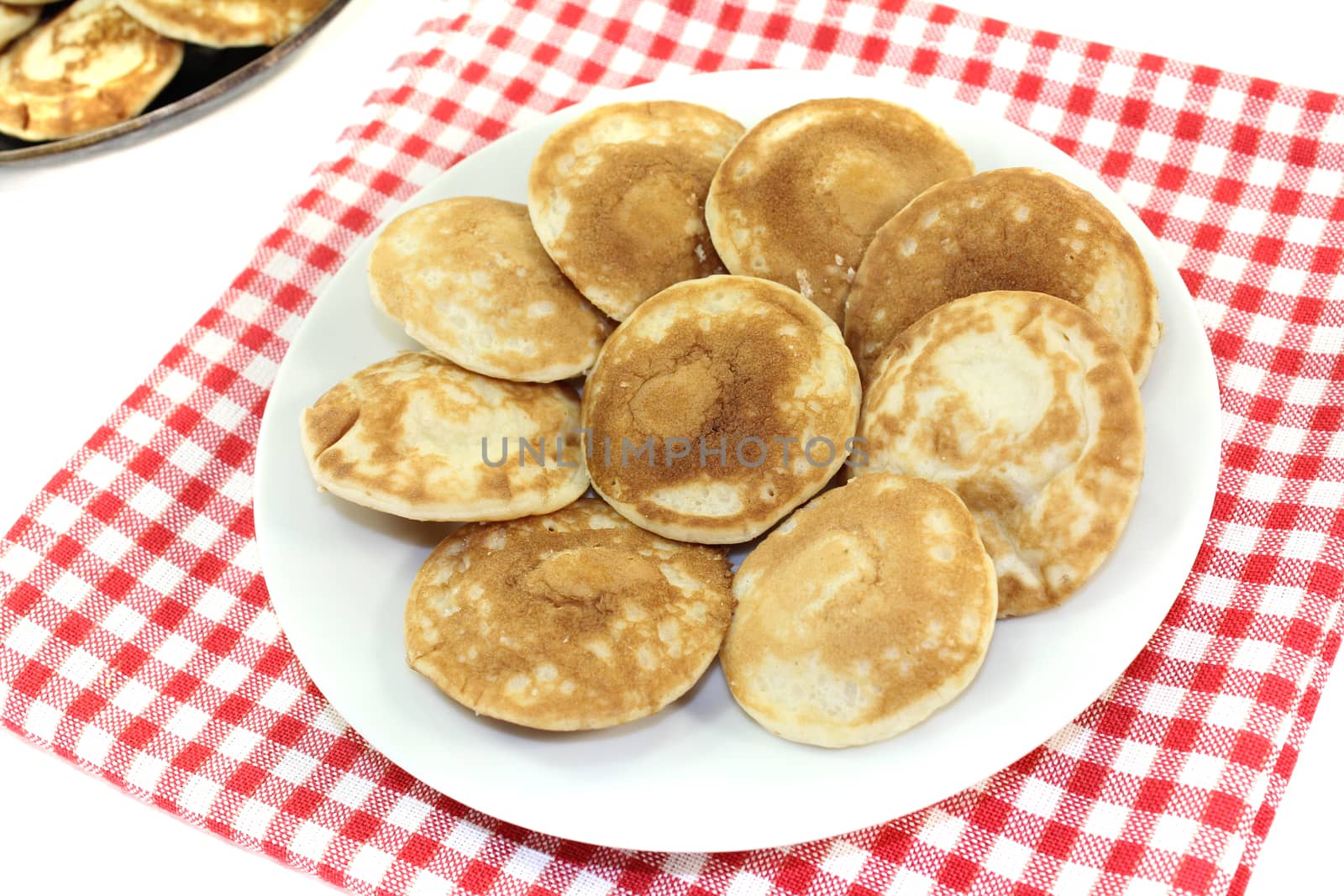 Dutch Poffertjes on a plate with napkin before light background