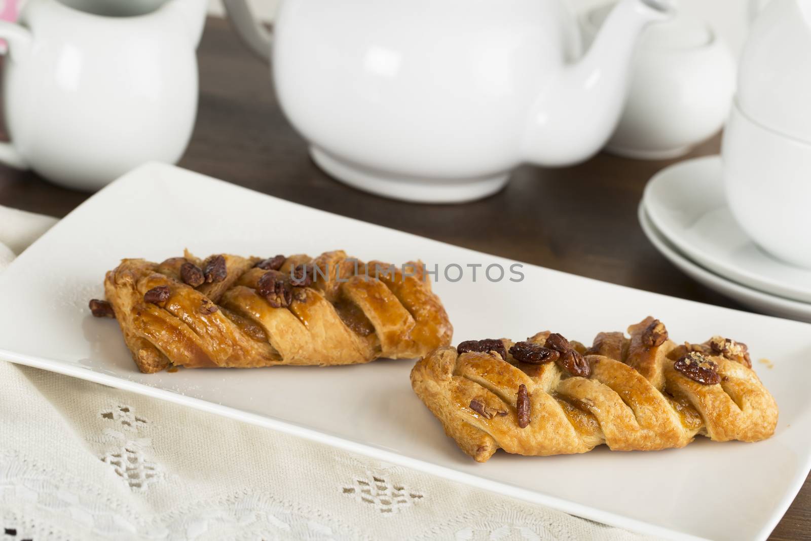 Morning pastries on serving plate with tea pot in background