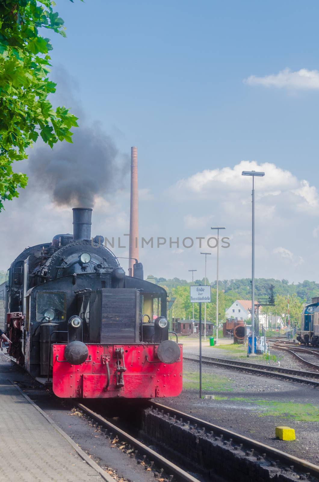 Directions and front view of a steam locomotive under full steam at the entrance to a train station.