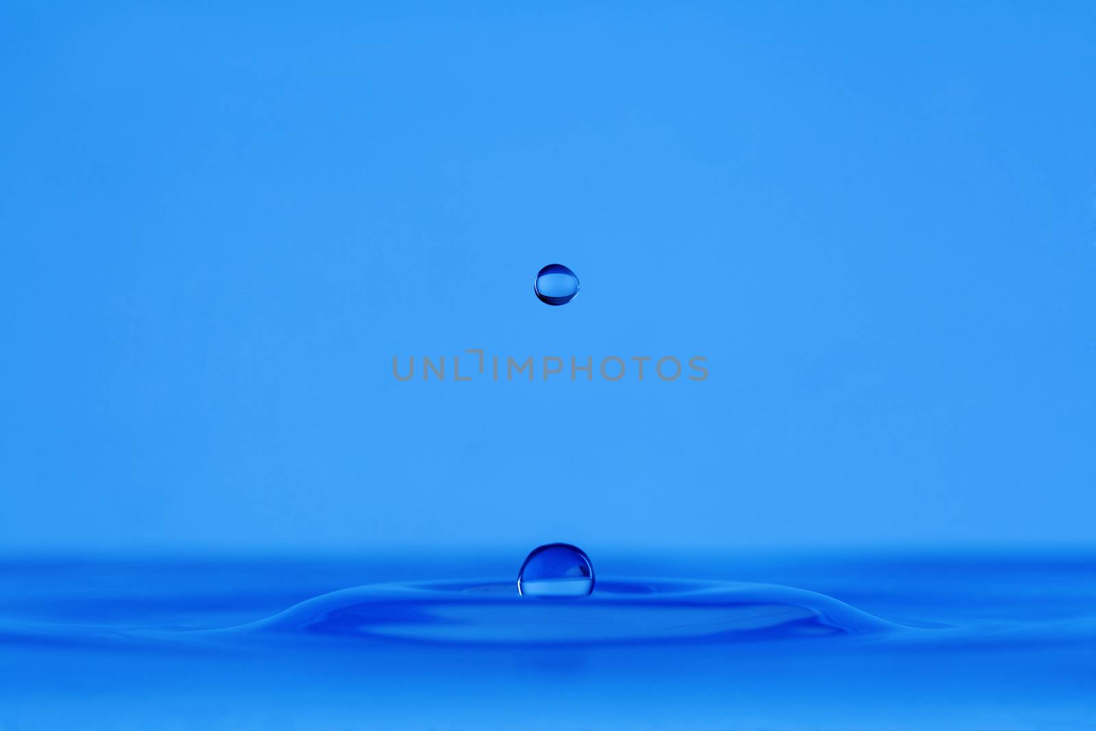 blue droplet hitting the water surface splashing it up